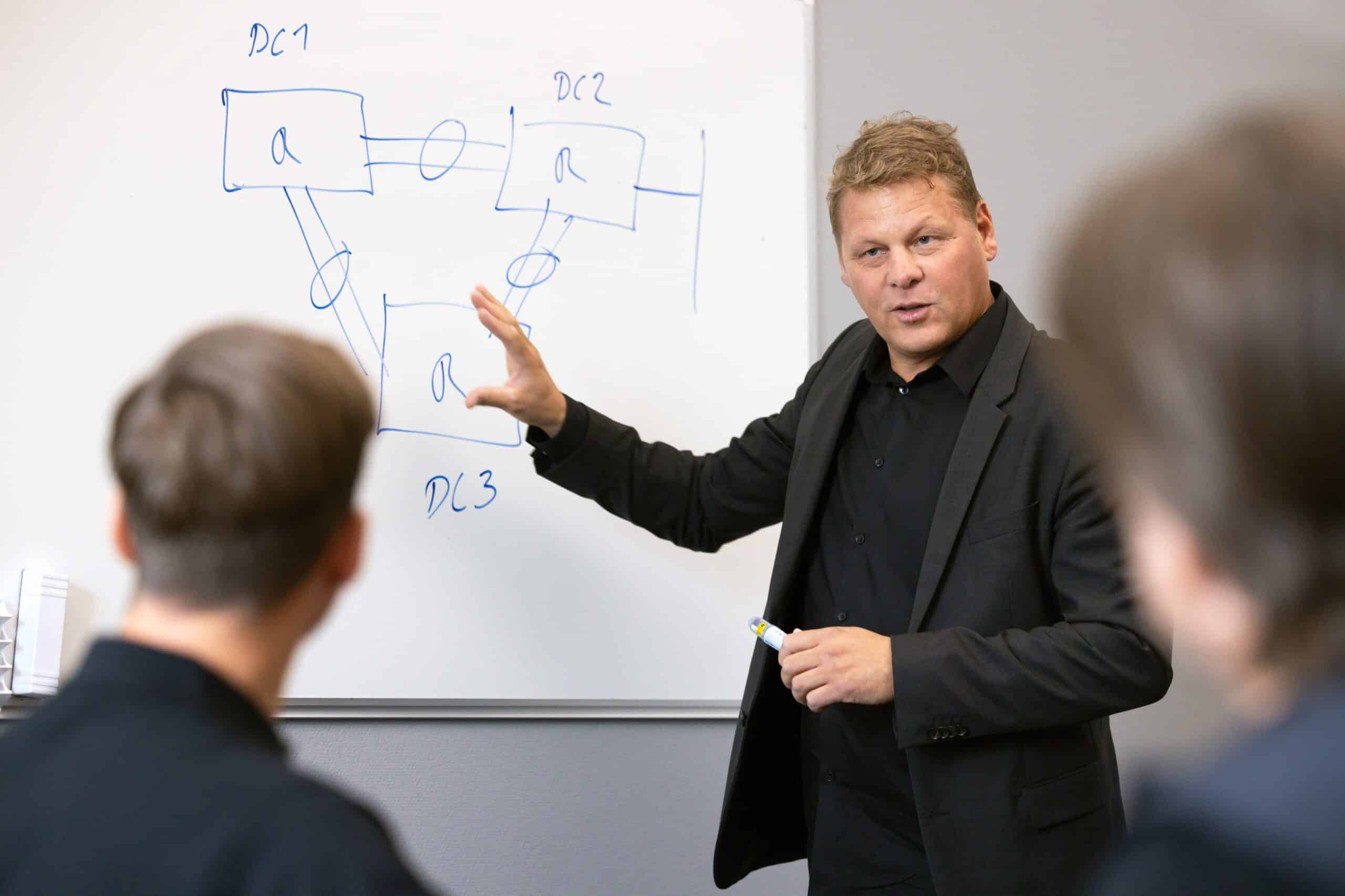 Man ritar och berättar framför en vit tavla.